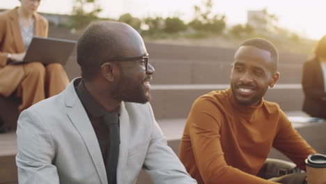 Two-Cheerful-African-American-Businessmen-Talking-over-Coffee-in-Park